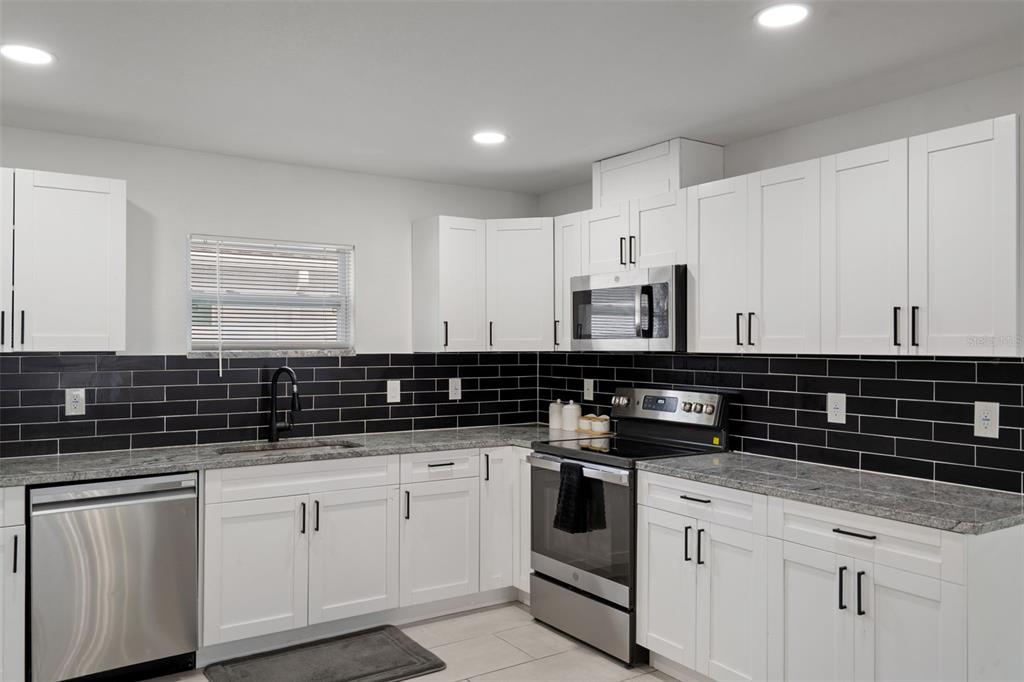 5106 Pacific Avenue Spring Hill, FL 34606 - Photo 11 of 23 a kitchen with granite countertop white cabinets and white appliances