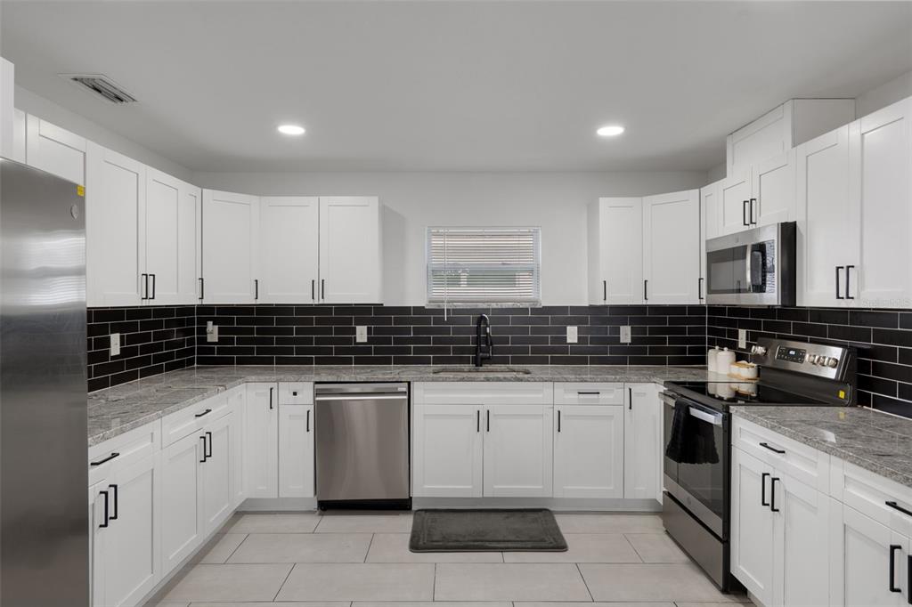 5106 Pacific Avenue Spring Hill, FL 34606 - Photo 10 of 23 a kitchen with granite countertop white cabinets and white appliances