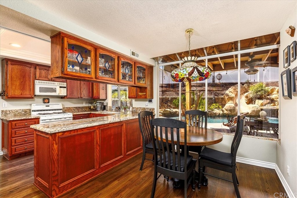 30152 Corte Carrizo Temecula, CA 92591 - Photo 13 of 45 a view of a kitchen with stainless steel appliances granite countertop a stove a refrigerator a dining table and chairs with wooden floor
