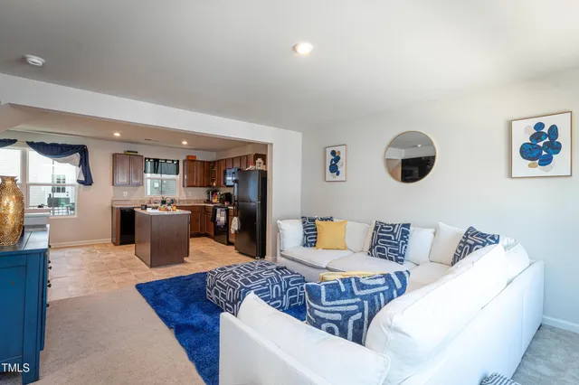 a living room with furniture kitchen view and a window