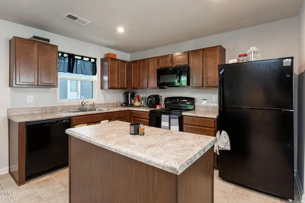 a kitchen with a refrigerator a sink a stove a microwave and wooden cabinets