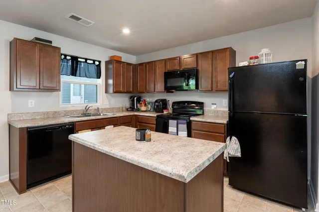 a kitchen with a refrigerator a sink a stove a microwave and wooden cabinets