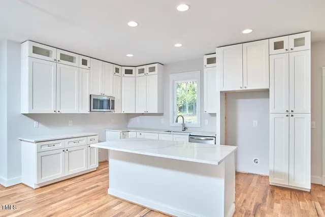 a kitchen with stainless steel appliances granite countertop a sink dishwasher a stove and white cabinets with wooden floor