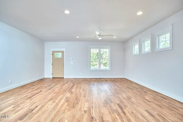 a view of empty room with wooden floor and fan