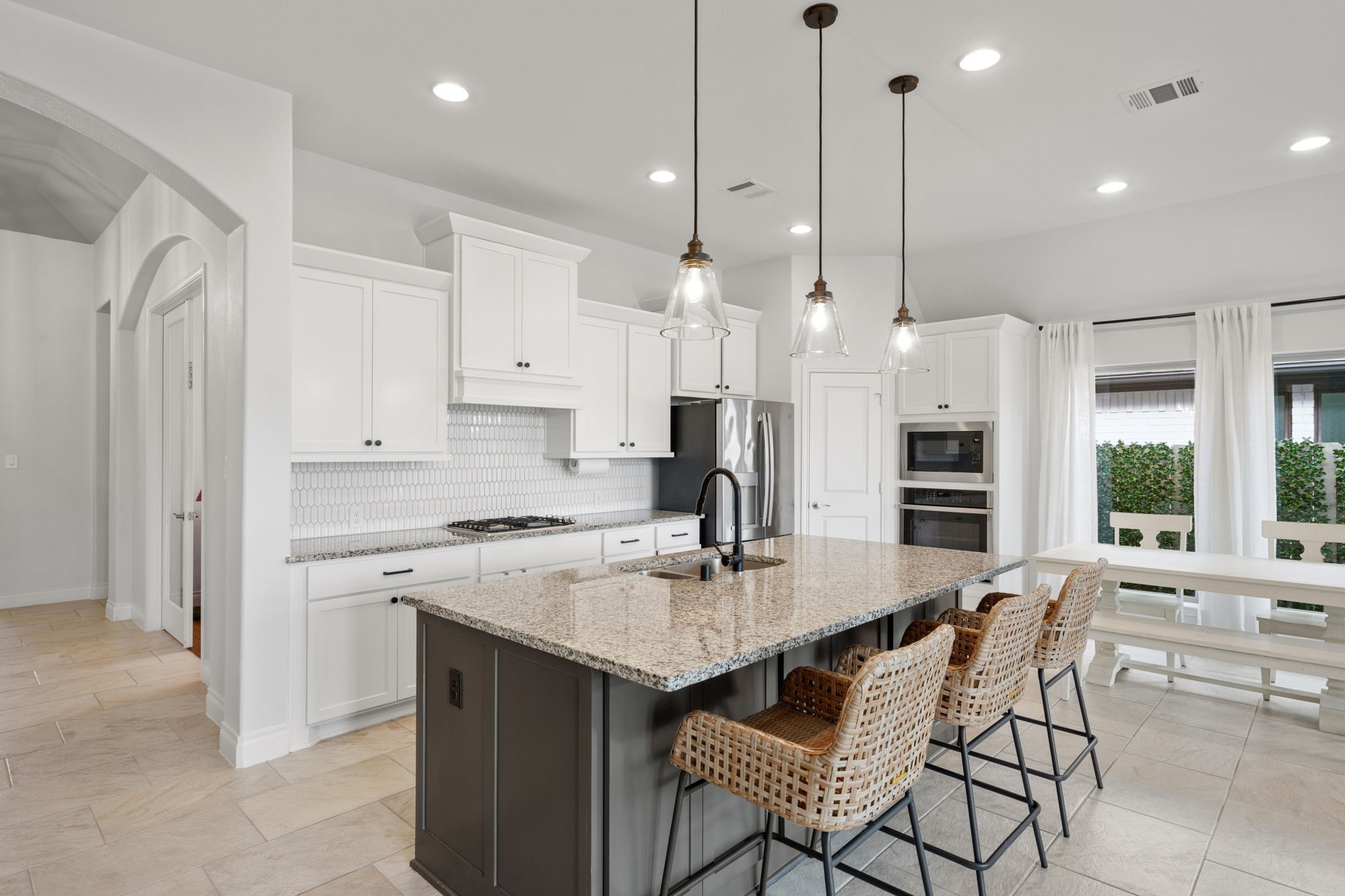 2119 Blackhawk Ridge Lane Manvel, TX 77578 - Photo 10 of 49 Chef's kitchen close-up showcasing granite countertops, elongated white picket tile backsplash, gas cooktop, and stainless steel built-in double oven and microwave combo.