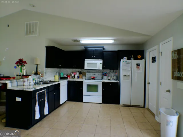 a kitchen with stainless steel appliances kitchen island granite countertop a refrigerator stove and sink