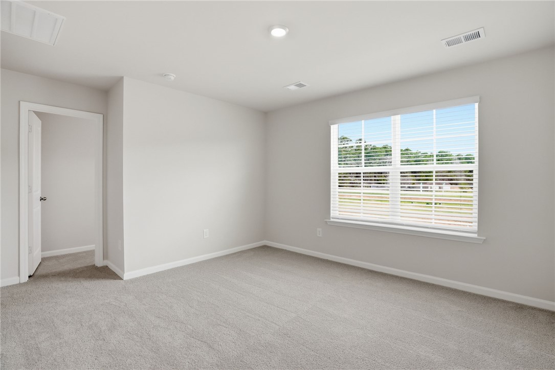 319 Lilac Loop Greenwood, SC 29649 - Photo 21 of 25 Bright and airy room with plush carpet, ideal for peaceful living.
