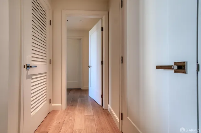 a view of a hallway with wooden floor and a bathroom