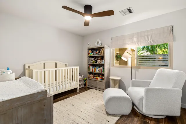 a room with a baby bed a couch and a book shelf