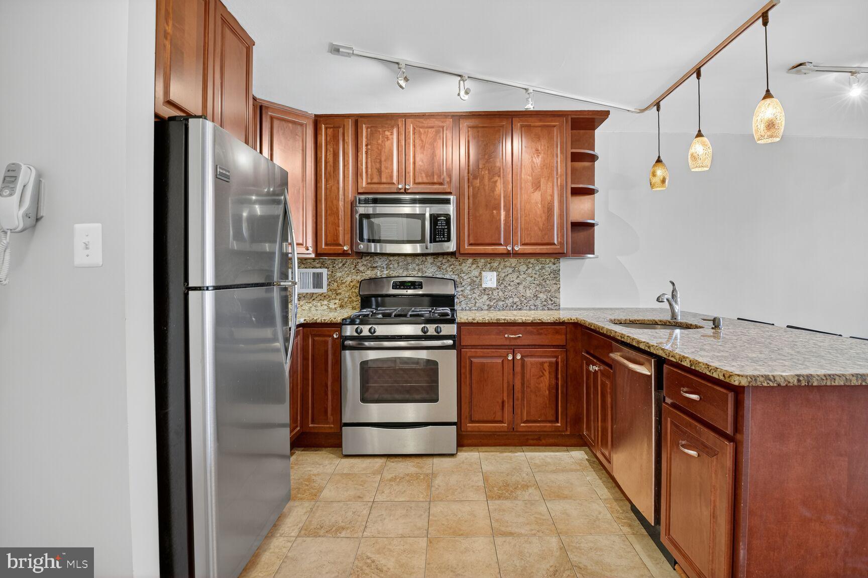 2939 Van Ness Street Northwest, Unit 941 Washington, DC 20008 - Photo 2 of 42 a kitchen with granite countertop stainless steel appliances and wooden cabinets