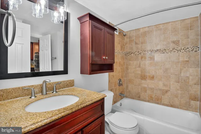 a bathroom with a granite countertop sink toilet mirror and shower