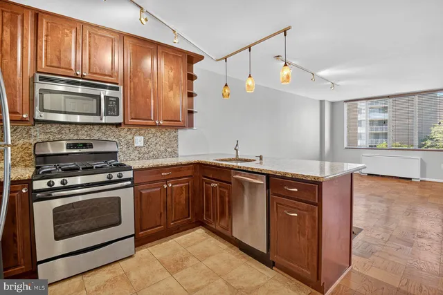 a kitchen with granite countertop wooden cabinets stainless steel appliances and a window