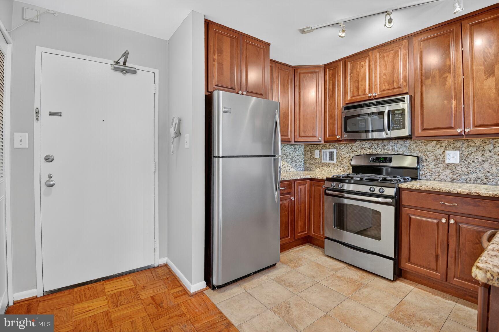 2939 Van Ness Street Northwest, Unit 941 Washington, DC 20008 - Photo 4 of 42 a kitchen with granite countertop stainless steel appliances and wooden cabinets