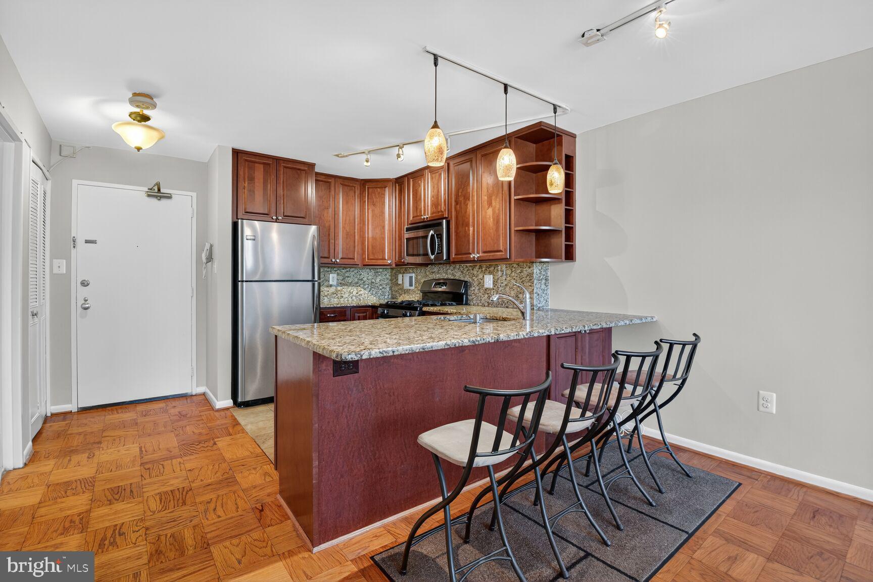 2939 Van Ness Street Northwest, Unit 941 Washington, DC 20008 - Photo 7 of 42 a kitchen with stainless steel appliances granite countertop a sink refrigerator and microwave