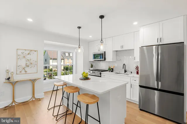 a kitchen with stainless steel appliances a refrigerator a stove a sink a dining table and chairs