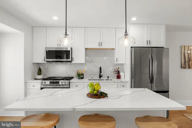 a kitchen with stainless steel appliances a stove a sink a refrigerator a microwave a stove and white cabinets