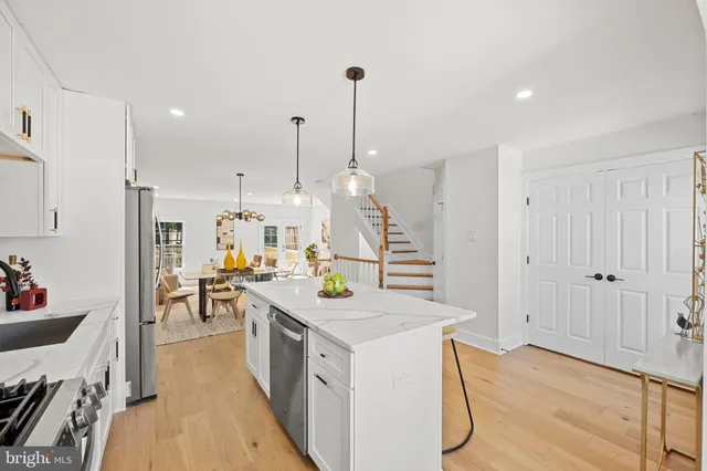 a kitchen with kitchen island a stove a sink a dining table and chairs with wooden floor