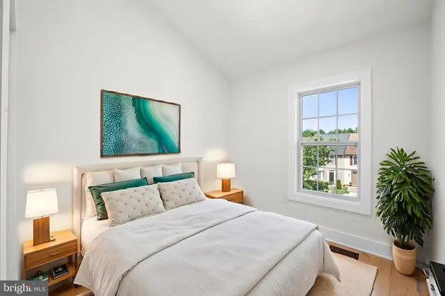 a bedroom with a bed and a potted plant next to a window
