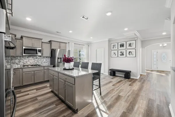 a kitchen with stainless steel appliances kitchen island granite countertop a table chairs in it and wooden floors