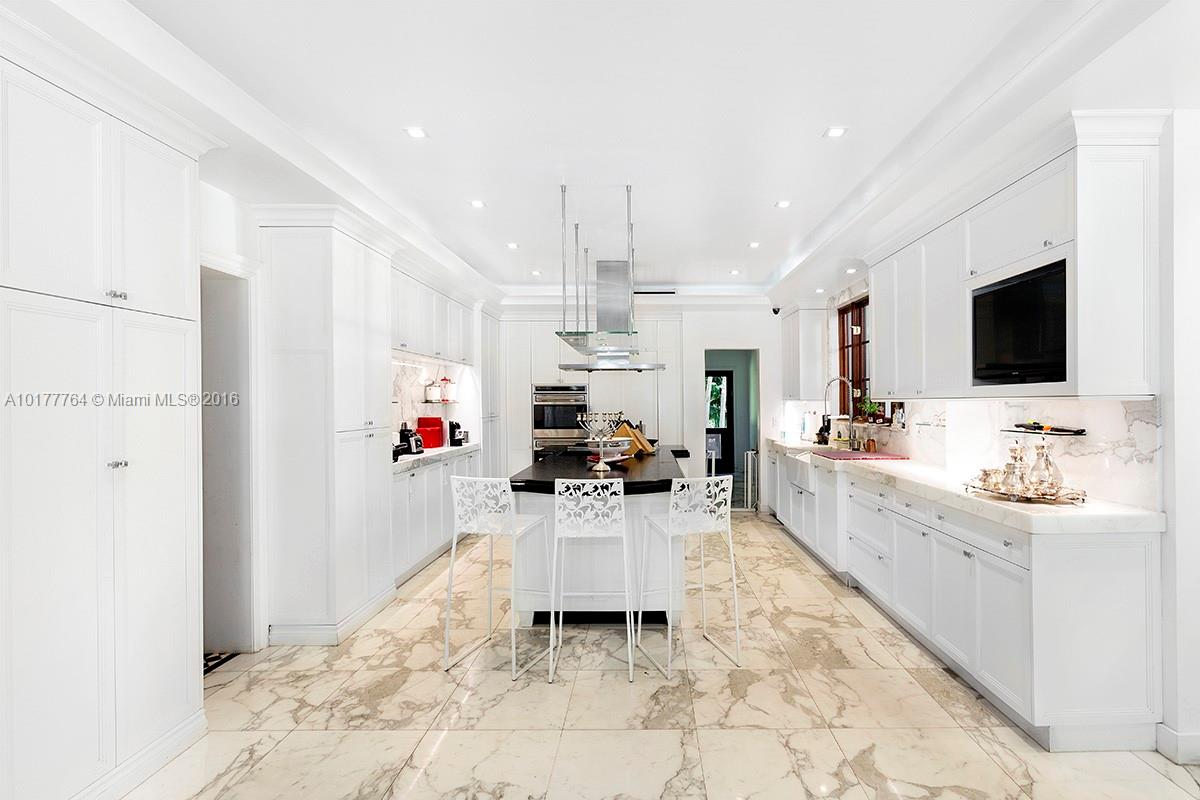 4855 Pine Tree Drive Miami Beach, FL 33140 - Photo 5 of 26 a large white kitchen with a refrigerator a sink dishwasher a oven with a dining table and chairs