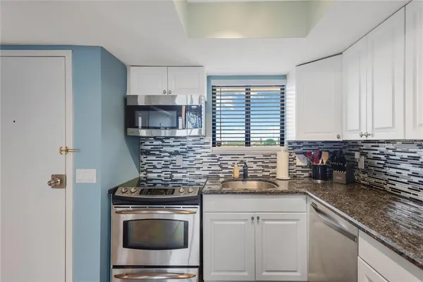 a kitchen with stainless steel appliances granite countertop a stove a sink and a microwave
