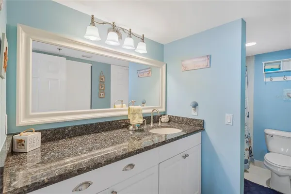 a bathroom with a granite countertop sink a toilet and a mirror