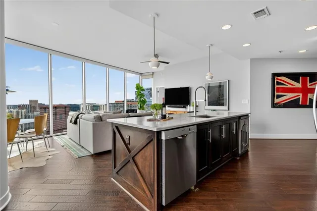 a kitchen with stainless steel appliances granite countertop a stove a refrigerator a kitchen island a dining table and chairs with wooden floor