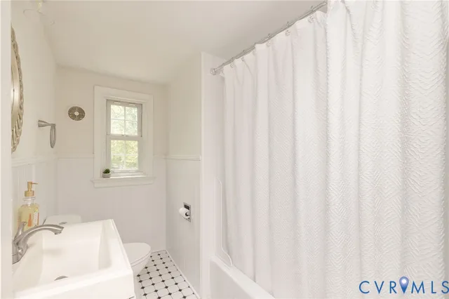 a bathroom with a sink a toilet and shower curtain