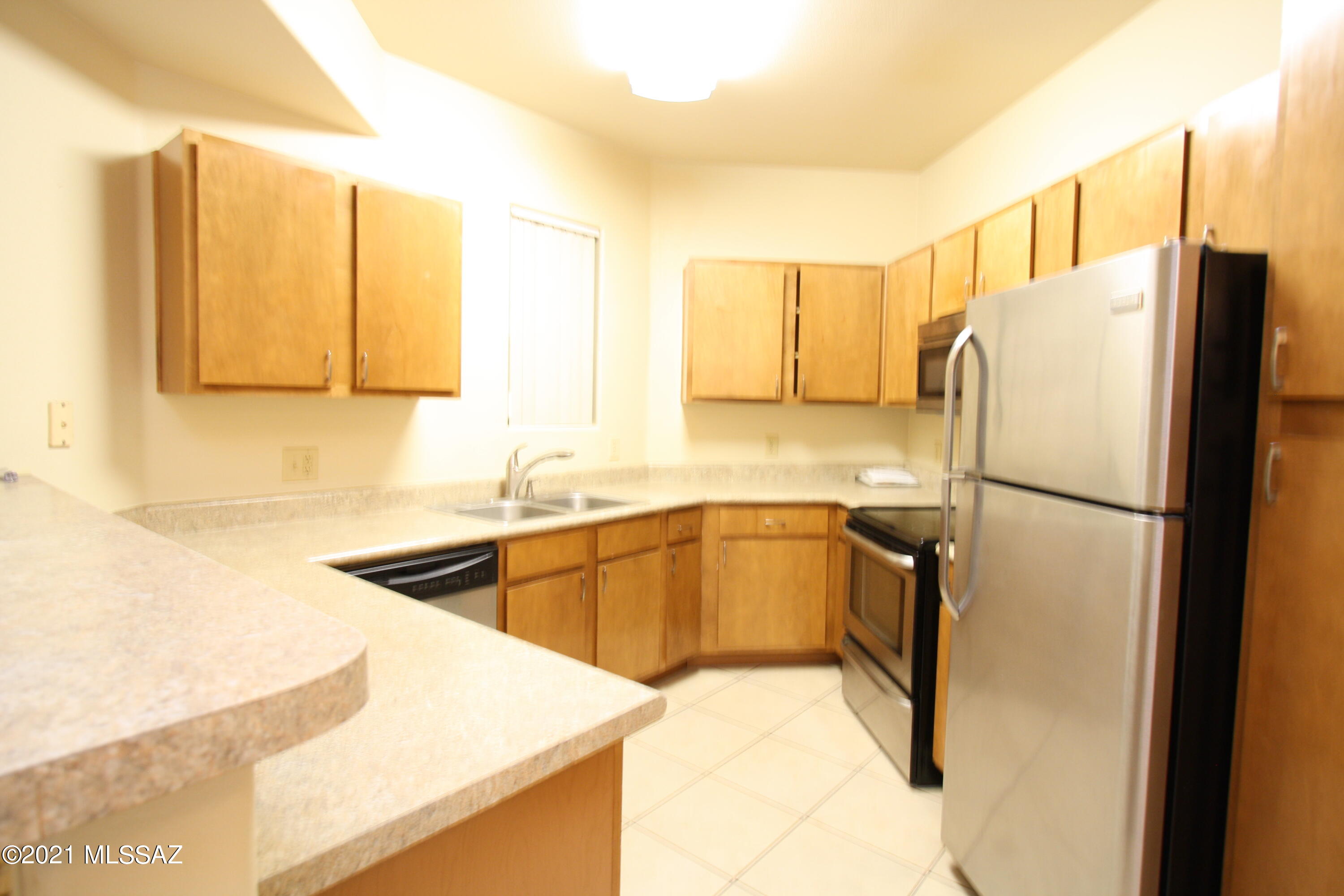 2550 East River Road, Unit 5104 Tucson, AZ 85718 - Photo 7 of 14 a kitchen with a refrigerator a sink and a cabinets