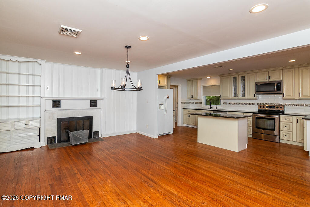 755 White Oak Road Cresco, PA 18326 - Photo 12 of 50 a large kitchen with kitchen island a stove a refrigerator a sink dishwasher with a fireplace and wooden floor