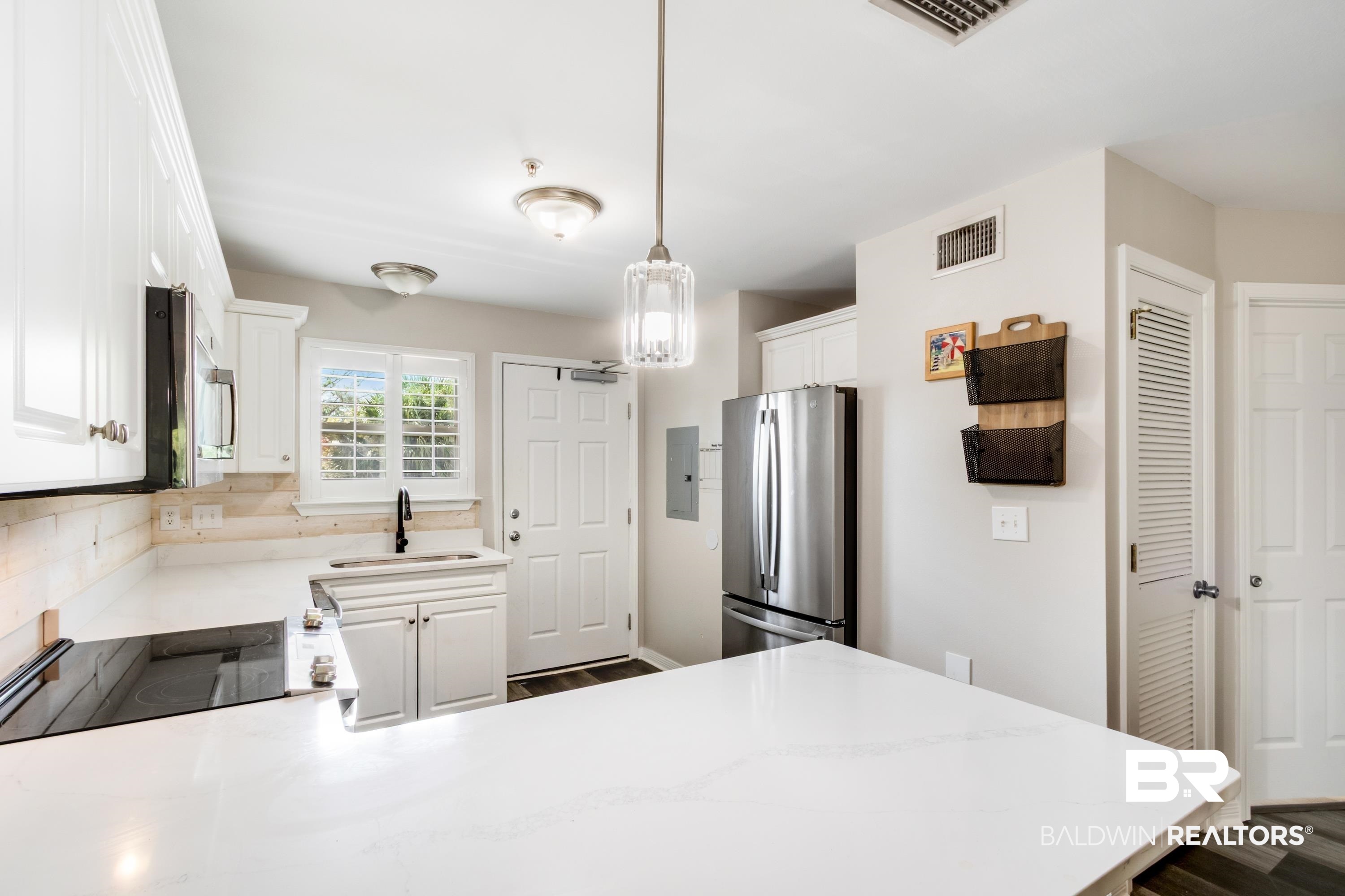 25957 Canal Road, Unit 208 Orange Beach, AL 36561 - Photo 6 of 28 Kitchen featuring white cabinetry, light-toned countertops, stainless steel refrigerator, and wood-finish flooring