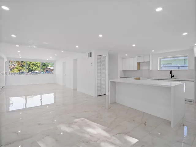 a view of a kitchen with kitchen island a sink stainless steel appliances and cabinets
