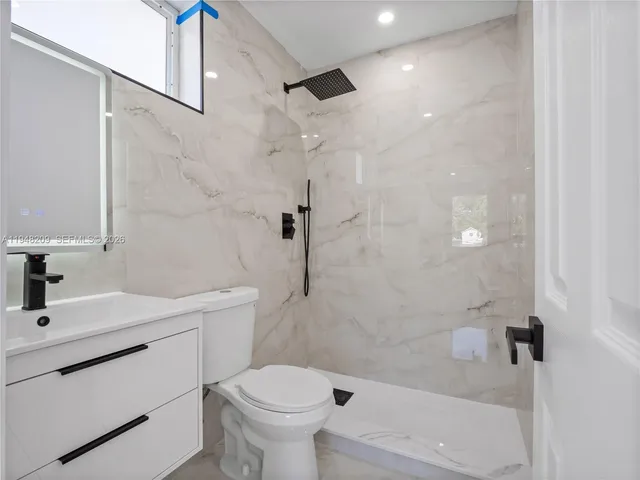 a bathroom with a sink toilet vanity and shower