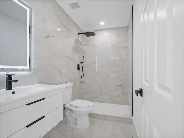 a bathroom with a toilet sink vanity and shower