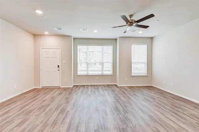 a view of empty room with wooden floor and window