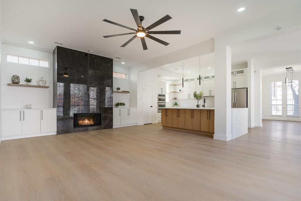 7524 Aberdon Road Dallas, TX 75252 - Photo 10 of 39 Unfurnished living room featuring light wood finished floors, ceiling fan, and a tile fireplace