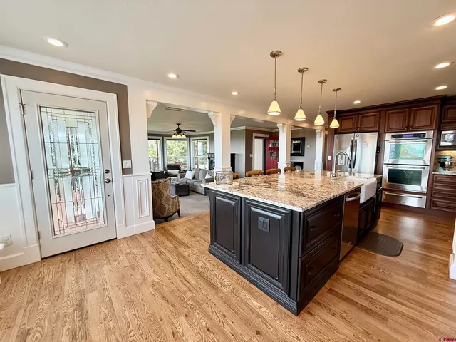 a kitchen with stainless steel appliances granite countertop a large kitchen island and a wooden floors