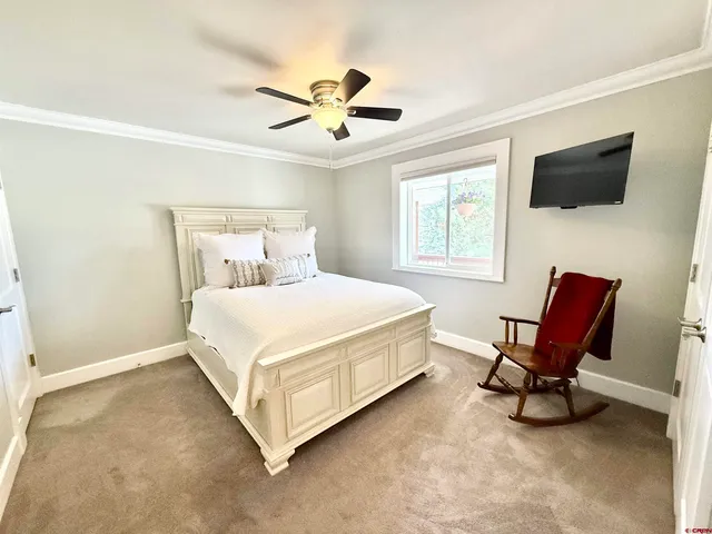 a bedroom with a bed a chair and flat screen tv