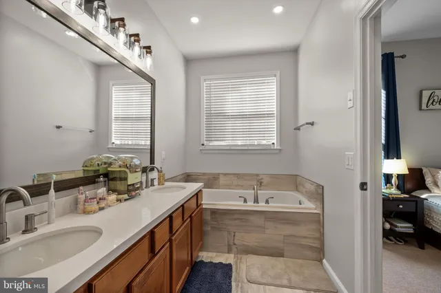 a bathroom with a tub double vanity sink and mirror