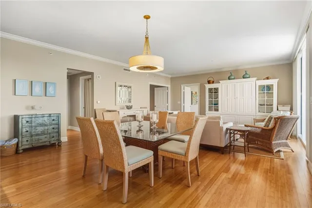 a dining room with wooden floor a chandelier a glass table and chairs
