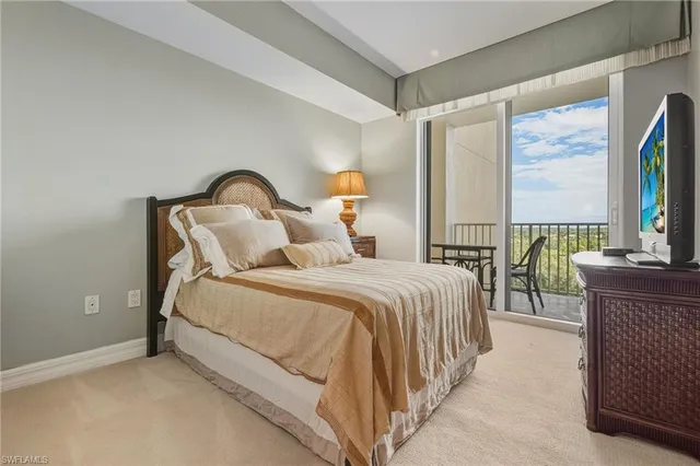 a bedroom with bed and a flat tv screen on dresser