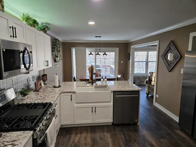 a kitchen with stainless steel appliances white cabinets a sink a stove a microwave and wooden floors