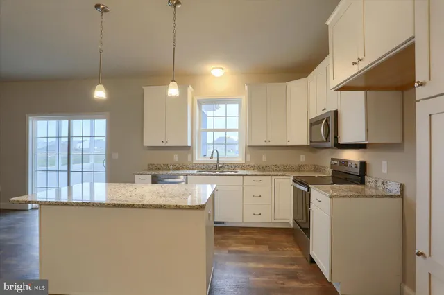 a kitchen with granite countertop a sink a window stainless steel appliances and cabinets