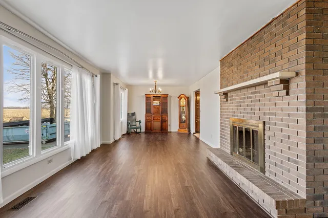 a view of a livingroom with wooden floor and a fireplace