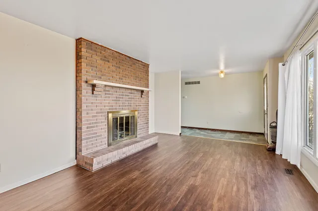 an empty room with wooden floor fireplace and windows