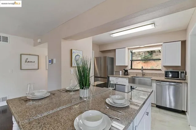 a kitchen with granite countertop kitchen island stainless steel appliances a sink and living room view