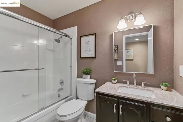 a bathroom with a granite countertop sink toilet a mirror a vanity and shower
