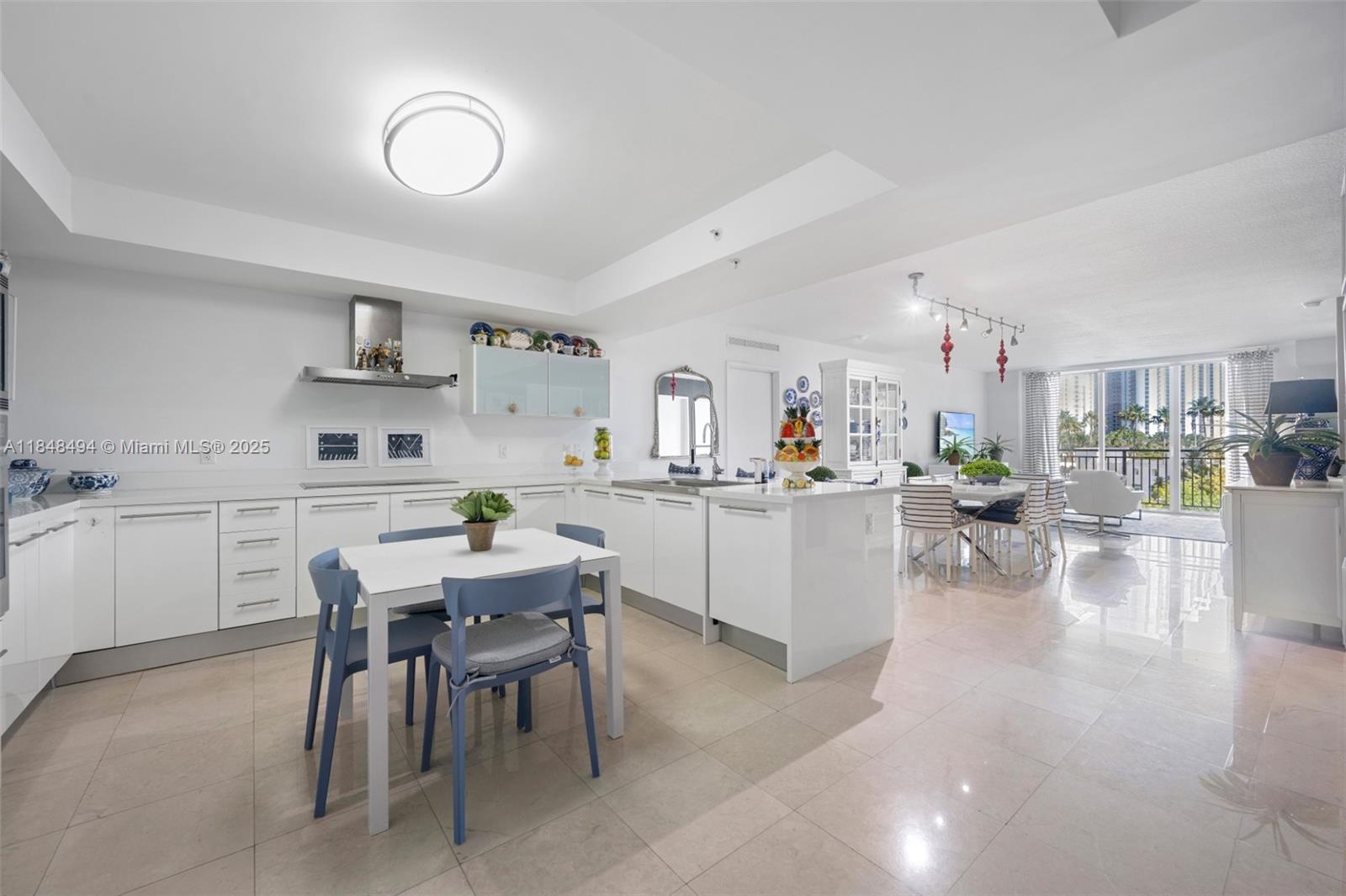 150 Sunny Isles Boulevard, Unit TH301 Sunny Isles Beach, FL 33160 - Photo 8 of 25 a kitchen with a dining table chairs and white cabinets