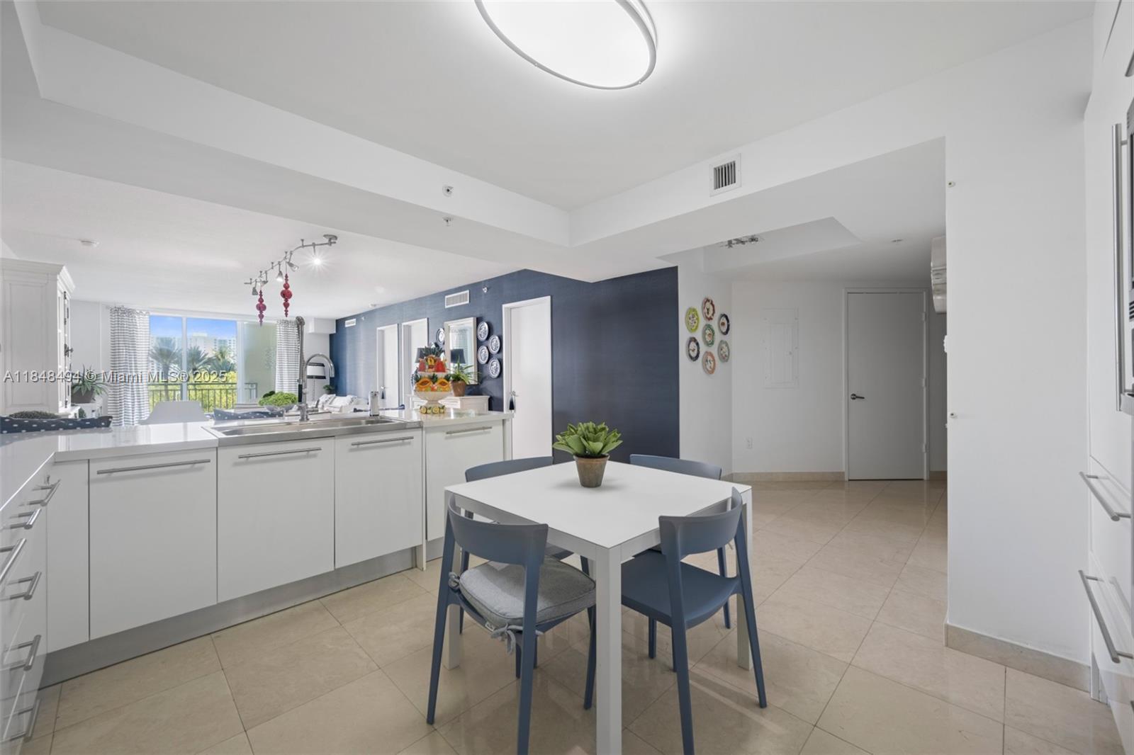150 Sunny Isles Boulevard, Unit TH301 Sunny Isles Beach, FL 33160 - Photo 9 of 25 a kitchen with a dining table chairs and white cabinets