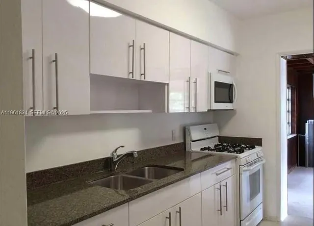 a kitchen with stainless steel appliances granite countertop a sink a stove and a granite counter top